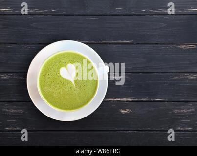 Eine Schale Matcha Latte trinken mit gezogenen kleinen Herzen auf der schwarzen Holztisch, Ansicht von oben Stockfoto