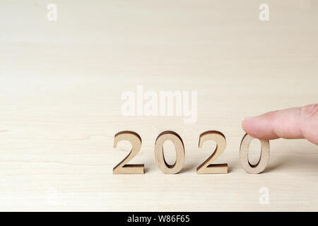 Hand legt Holz- Zahlen auf dem Tisch, als Symbol für das Jahr 2020 neues Jahr Stockfoto