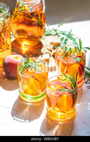 Gläser süßer Pfirsich Eistee, Sommer kalt Pfirsich fizz Cocktail mit Rosmarin. Sonnigen Licht. Geringe Tiefe des Feldes, Nahaufnahme, kopieren Sie Raum für Sie Stockfoto