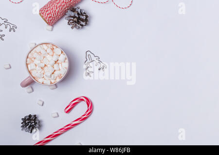 Weihnachten flach mit Kakao und Marshmallows, Zuckerstangen und Tannenzapfen auf weißem Hintergrund Stockfoto