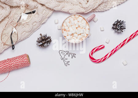 Weihnachten Zusammensetzung mit Kakao, Marshmallows, gestrickte Pullover und andere traditionelle Objekte auf dem weißen Hintergrund, Ansicht von oben Stockfoto