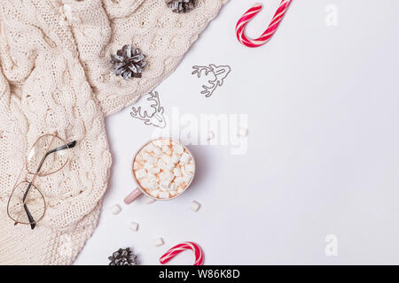 Weihnachten Zusammensetzung mit Kakao, Marshmallows, gestrickte Pullover und andere traditionelle Objekte auf dem weißen Hintergrund, Ansicht von oben Stockfoto