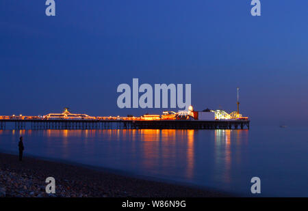 Langsame Exposition, bei Sonnenuntergang von Brighton Pier aus den Strand genommen, East Sussex England mit Motion Blur von Wellen Stockfoto