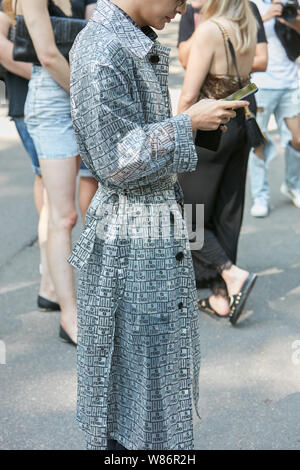 Mailand, Italien - 17. JUNI 2019: Mann mit grauen und schwarzen Regenmantel mit Fendi-Logos auf Smartphone, bevor Fendi fashion show, Mailand Fashion Week st Stockfoto