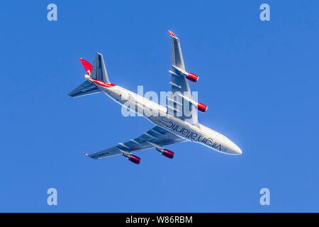 Suchen Sie auf der Unterseite des Virgin Atlantic Flugzeug, G-VXLG, einer Boeing 747-41 R Flugzeuge, fliegen hoch gegen den blauen Himmel in Großbritannien. Stockfoto