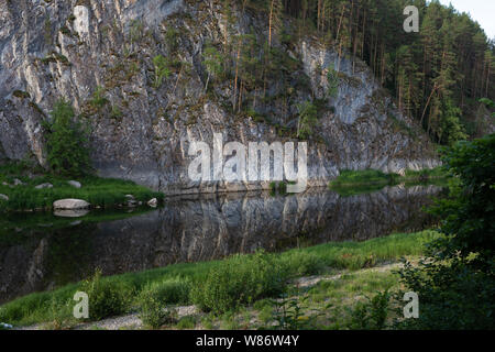 Schöne Landschaft, der Fels ist in einer ruhigen mountain river nieder, um den Wald und grünes Gras. Hintergrund für das Design oder Foto Tapete. Stockfoto