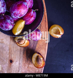 Lecker saftig blaue Pflaumen in einer Schale auf dem Tisch, strukturierte Holztisch, natürliche Materialien und natürliche umweltfreundliche Produkte, gesundes Essen. Stockfoto