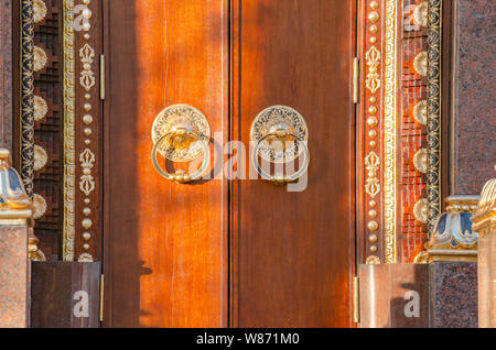 Alte hölzerne Tor mit zwei goldenen Türklopfer in der Nähe Ringe vorne sehen. Alte Tür Fragment des buddhistischen Tempel Datsan Gunzechoyney. Stockfoto