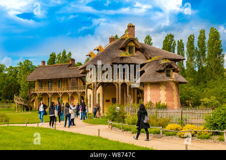 Besucher bewundern das Haus der Königin und Billardraum im Weiler das Trianon in Versailles. Die beiden rustikalen Gebäuden sind verbunden durch eine... Stockfoto