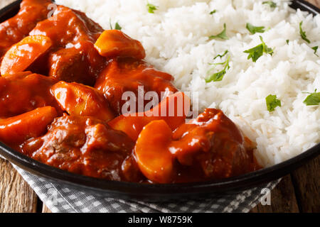 Hausgemachte Rinderragout mit Äpfeln in Tomatensauce serviert mit Reis closeup auf einem Teller auf den Tisch. Horizontale Stockfoto