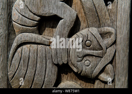 Detail Foto des Outdoor Wood carving auf den vertikalen Balken an der hölzernen Stabkirche, die Ansgar Kirche aus dem Jahr 855 im Ribe Viking Center in Lostrupholm in der Nähe von Ribe, Dänemark. Bei archäologischen Ausgrabungen in der Nähe Ribe Dom bleibt gefunden wurden, zeigt auf, dass eine christliche Gemeinschaft und eine Kirche vorhanden waren, so früh wie 855. Keine Überreste von Holzschnitzereien wurde gefunden und die Schnitzereien hier von anderen gründet in Dänemark und aus der Umgebung von Hamburg, wo Bischof Ansgar von kam. Die Kirche an der Viking Center wurde im Jahr 2018 eingeweiht. [Hinweis: DIESES FOTO IST STRIKT FÜR Stockfoto