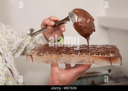 Gießen geschmolzene Schokolade in eine Form Schokolade zu machen. Stockfoto