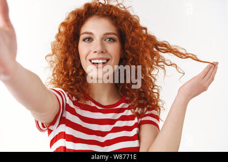 Lebendige gut aussehende redhead lockigen Haaren, blauen Augen fröhliche Frau spielen Lächeln glückliche Hand tippen Sie auf Kamera, selfie Record blog video Nachricht curl Stockfoto