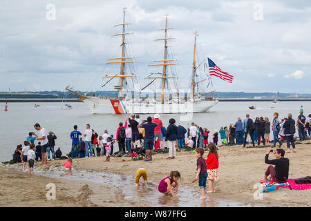 Zuschauer verfolgen die Tall Ship US Küstenwache USCGC Eagle (WIX-327), der Rückkehr von der Armada Rouen vom Strand von Honfleur, Normandie, Frankreich Stockfoto