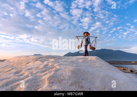 Frau hart arbeiten durch die schwere Salz Körbe auf ihren Schultern am frühen Morgen Hon Khoi Salz Feld, Nha Trang Provinz, Vietnam Stockfoto