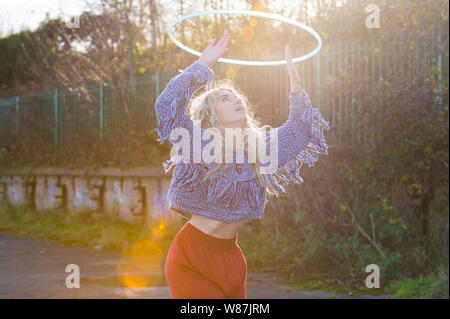 Mädchen schaut bis zu einem Hoop, über Ihrem Kopf, fthree viertel Länge. Flare von Sun. Stockfoto