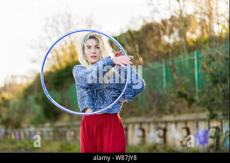 Mädchen schaut durch einen Reifen, direkt an der Kamera, drei Viertel Länge. Stockfoto