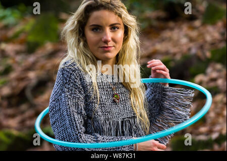 Mädchen schaut direkt in die Kamera, Spinning einen Reifen um ihre Schultern, im Wald Posing, kopieren. Stockfoto