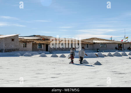 Salar de Uyuni, Uyuni, Bolivien: Die Menschen in den weißen Salzflächen wandern mit Schaufeln zu meinen das Salz in bolivianischen Salzwüste Stockfoto