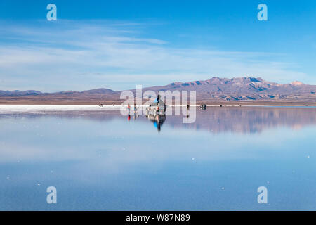 Wasser Spiegel in der Salar de Uyuni, Uyuni, Bolivien: Touristen reflektiert in weißen Salzflächen See und Jeep Tour Aktivitäten in bolivianischen Salz Wüste genießen Stockfoto