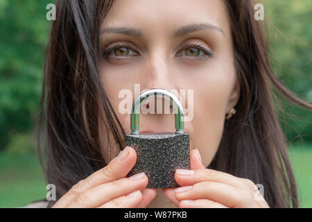 Konzeptionelle Porträt einer Frau halten Stille mit Verriegelung über ihren Mund. kaukasische Frau Mund gesperrt. Sprachbarriere Konzept und schützen. Stockfoto