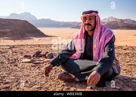 Ein Beduinen-Mann sitzt vor dem Hintergrund der jordanischen Wüste Wadi Rum oder Tal des Mondes Stockfoto