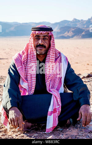 Ein Beduinen-Mann sitzt vor dem Hintergrund der jordanischen Wüste Wadi Rum oder Tal des Mondes Stockfoto