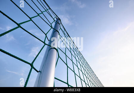 Eine silberne Stange mit einem Netz Gebäude einen Zaun gegen die blauen Abendhimmel Stockfoto