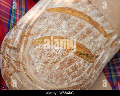 Laib hausgemachtes Brot mit Picknickdecke im Hintergrund Stockfoto