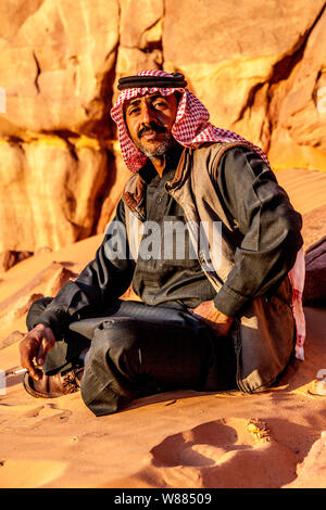 Ein Beduinen-Mann sitzt vor dem Hintergrund der jordanischen Wüste Wadi Rum oder Tal des Mondes Stockfoto