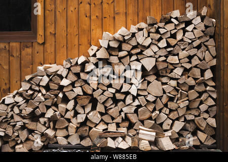Stapel von Holz. Woodpile von Brennholz in der Nähe einer Holzwand. Winter Home comfort Konzept. Stockfoto