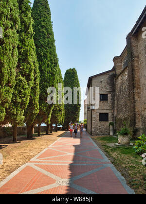 Touristen schlendern Sie durch den Garten der Kirche Santa Maria della Neve in dem Dorf Sirmione am Ufer des Gardasees in Italien Stockfoto