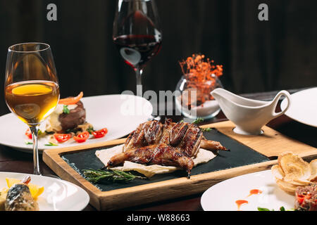 Gegrilltes Rebhuhn, Seebarsch, Tartaros. Verschiedene Gerichte auf den Tisch im Restaurant Stockfoto