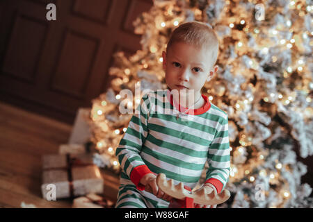 Die junge Mutter und ihr Sohn im festlichen Schlafanzug während der Weihnachtsfeier Stockfoto