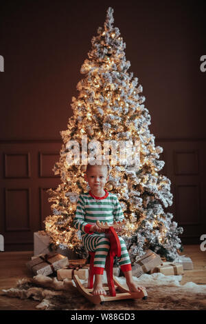 Die junge Mutter und ihr Sohn im festlichen Schlafanzug während der Weihnachtsfeier Stockfoto