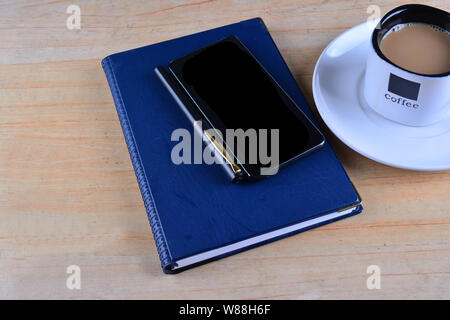 Leer Notebook, Füllhalter, Smartphone und Tasse Kaffee auf Schreibtisch Stockfoto