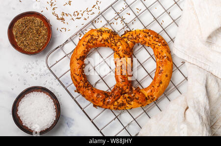 Frisch gebackene Brezel mit grobem Salz und Kümmel. Gourmet Snacks und Zutaten auf den Tisch. Selektiver Fokus Stockfoto