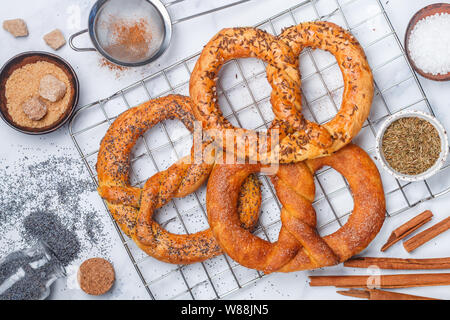 Brezel. Frisch gebackene Brezeln mit Zucker, Mohn, Zimt und Kreuzkümmel. Köstlichen hausgemachten süßen und salzigen Backwaren und Zutaten auf den Tisch. Stockfoto