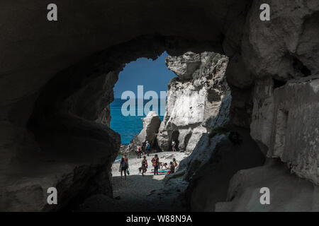 Ein wunderschöner Strand, erreichbar durch einen Tunnel in einen Felsen mit einigen Menschen. Sizilien, Italien.
