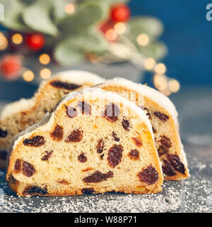 Christstollen auf blau-grünen Hintergrund mit festlichen Weihnachtsbeleuchtung und roten Beeren im Winter, kopieren - Raum. Traditionelle deutsche Dessert für Weihnachten celeb Stockfoto