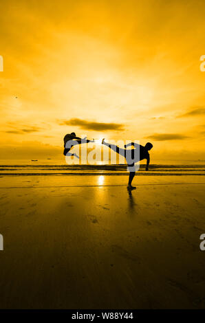 Kampf gegen einen Feind in der Nähe des Strandes, wenn die Sonne untergeht Stockfoto