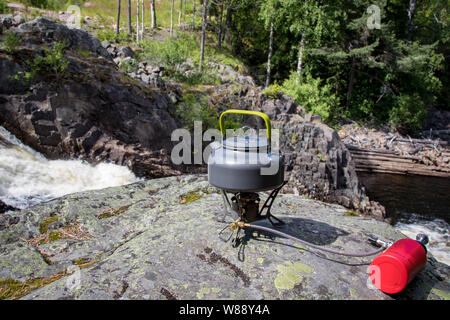 Camping Herd und Wasserkocher auf einem Felsen am Fluss im Freien Stockfoto