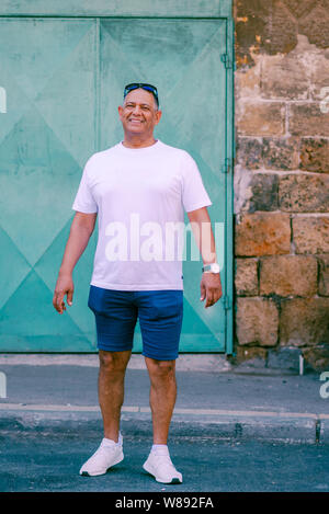 Senior touristische athletische im Nahen und Mittleren Osten Mann auf der Straße, genießen Sie einen wunderschönen Blick auf die Altstadt. Reisen, Freiheit, aktiven Lebensstil Konzept. Business lächelnd reifer Mann in Shorts und T-Shirt auf Urlaub. Stockfoto