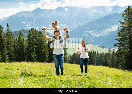 Familie mit Tochter halten sich an den Händen, die auf Feld, in den Bergen Stockfoto