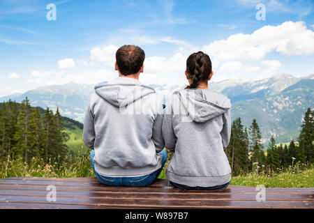 Paar sitzt auf der Bank mit Panoramablick auf die Berge Stockfoto