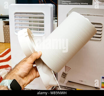 Paris, Frankreich, 23.Juni, 2019: Junger Mann unboxing Installieren neue tragbare Klimaanlage AC im heißen Sommer in seinem Wohnzimmer Inspektion der mitgeliefertes Zubehör Stockfoto
