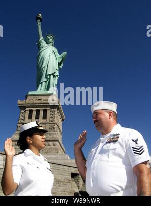 Jeder wirft ihre rechte Hand als Fähnrich Maria Navarro (links) verwaltet den Eid der Re-Eintragung zu Petty Officer 1st Class John Carruthers am Sockel der Freiheitsstatue auf Liberty Island, New York, die am 7. Juli 2000. Navarro und Carruthers sind zwei von über 25.000 internationalen Matrosen und Marines aus 20 Ländern in New York für Internationale Naval Review 2000 eine einwöchige Veranstaltung in Rechnung als Feier der Seapower für das Jahrtausend. Navarro und Carruthers sind an Bord der ticonderoga Klasse Cruiser USS Stadt Hue (CG66) stationiert. Stockfoto