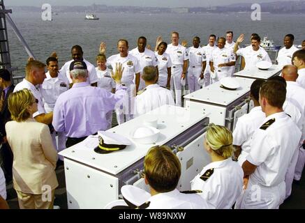 Präsident Bill Clinton (im blauen Hemd) liest den Eid der Re-Eintragung auf eine Gruppe von Matrosen an Bord der USS Stadt Hue (CG66) am 4. Juli 2000, in den Hafen von New York. Der Präsident wird an Bord der ticonderoga Klasse cruiser Marineeinheiten aus der ganzen Welt für die Internationale Naval Review 2000 zu überprüfen. First Lady Hillary Rodham-Clinton, Uhren die Zeremonie auf dem presidentХs links. Stockfoto