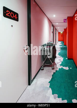 Hotel Gehweg Korridor mit 204 Zimmer Anzahl und Gebäudereinigung Warenkorb in der Nähe einer Wand rot leuchtenden Wände Stockfoto