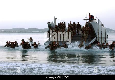 Us-Marines und Matrosen auf die 1 Flotte Antiterrorism Security Team, 7th Platoon zugeordnet, springen aus ihren Landing Craft und tauchen Sie ein in die Brandung während eines Pre-dawn Amphibisches Übung in Guantanamo Bay, Kuba, am 23. Juni 2004. Stockfoto